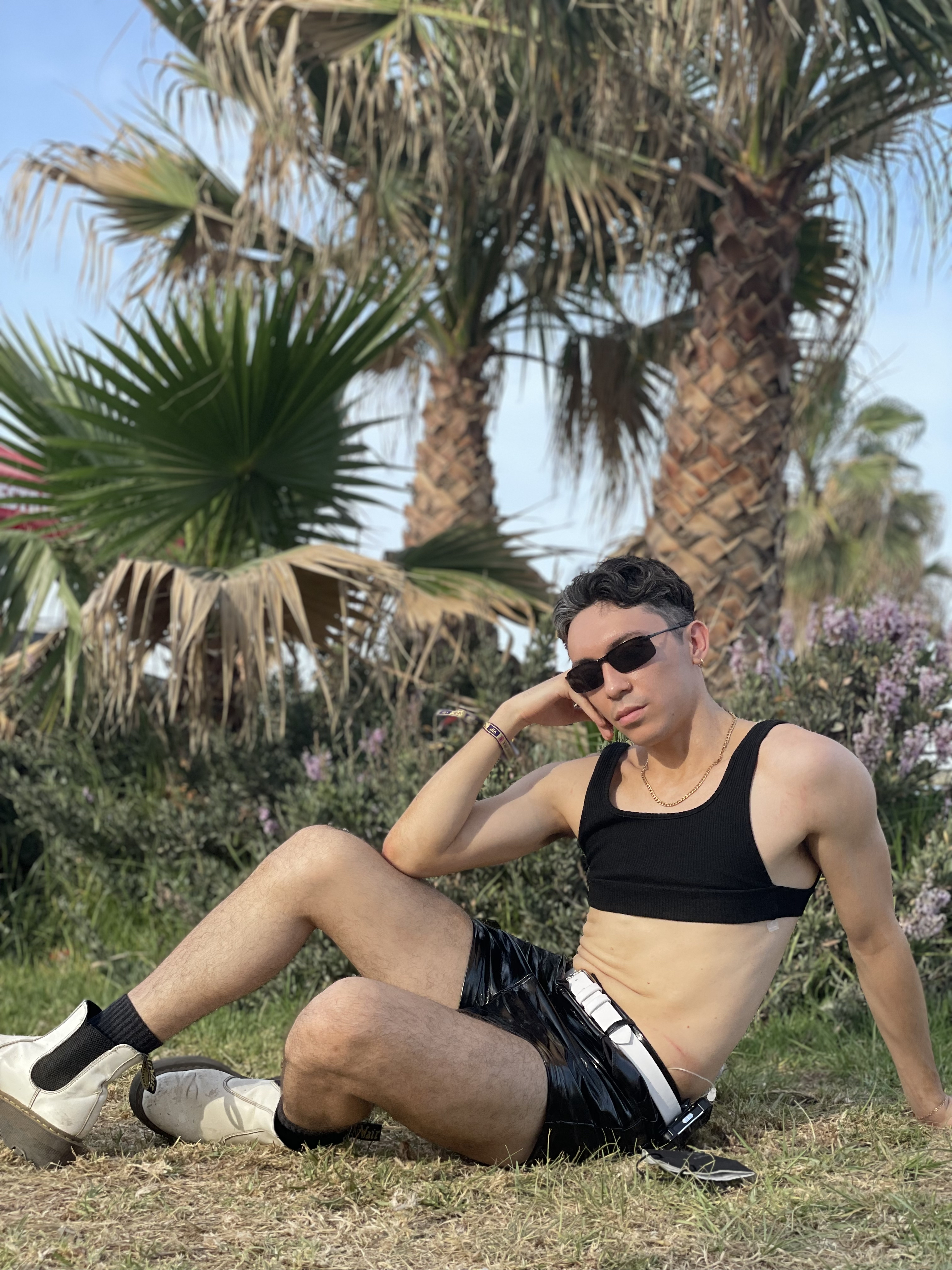 Stephen wearing black vinyl shorts, black crop tank, and techno sunglasses